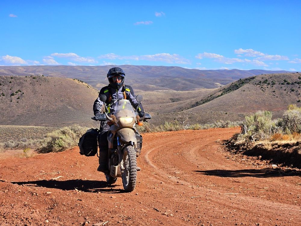Riding a loaded adventure motorcycle on a red dirt road through the high desert