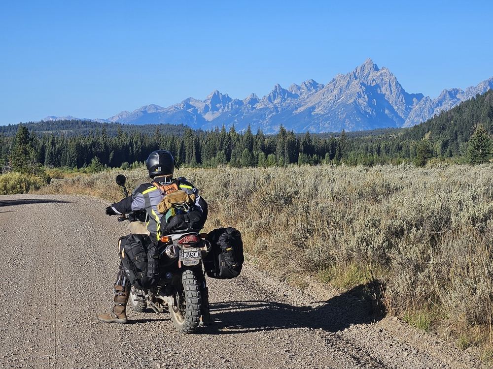 Motorcycle parked on a gravel road with the Tetons in the background